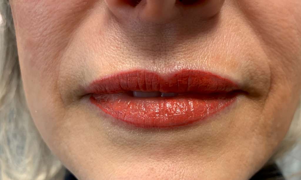 A close up of a woman 's lips with red lipstick.