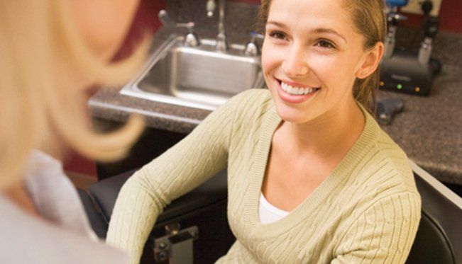 A woman is smiling while sitting in front of a sink.